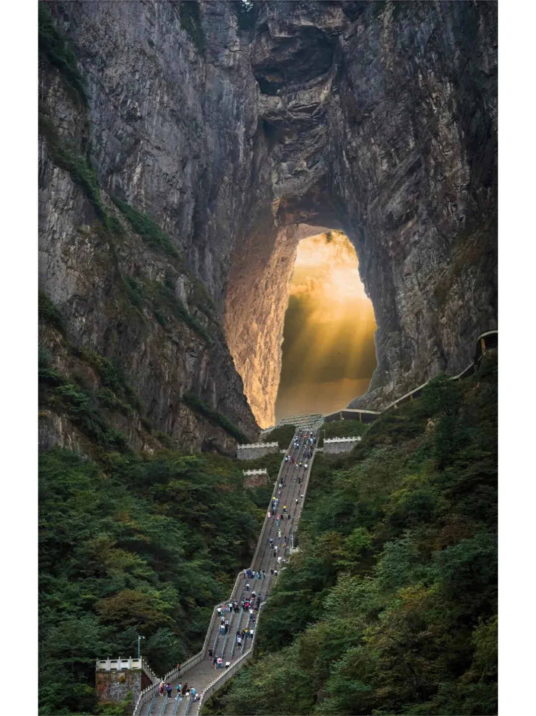 Tianmen Mountain, Zhangjiajie, hunan, china, chinatrip, A long stairway winds up a forested valley toward a massive rock arch with sunlight streaming through the opening.