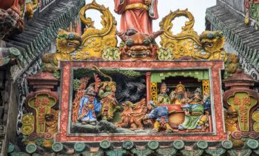 Chen Clan Ancestral Hall, guangzhou, china, chinatrip, Colorful Chinese temple facade with gold dragon heads and a detailed relief showing figures and a beast in a red frame at the center of the scene example of traditional temple art.