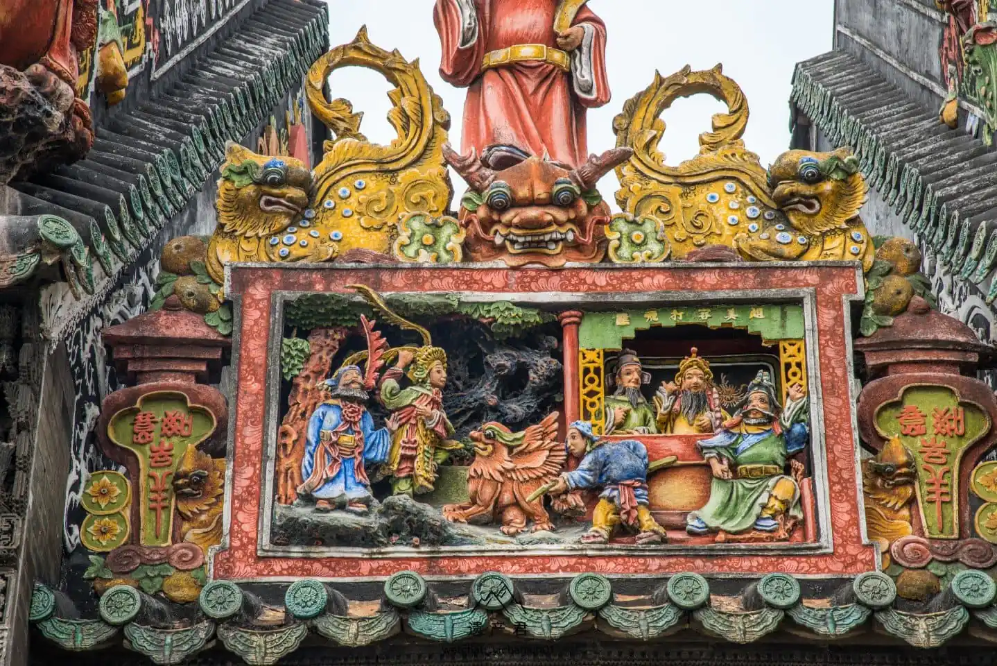 Chen Clan Ancestral Hall, guangzhou, china, chinatrip, Colorful Chinese temple facade with gold dragon heads and a detailed relief showing figures and a beast in a red frame at the center of the scene example of traditional temple art.