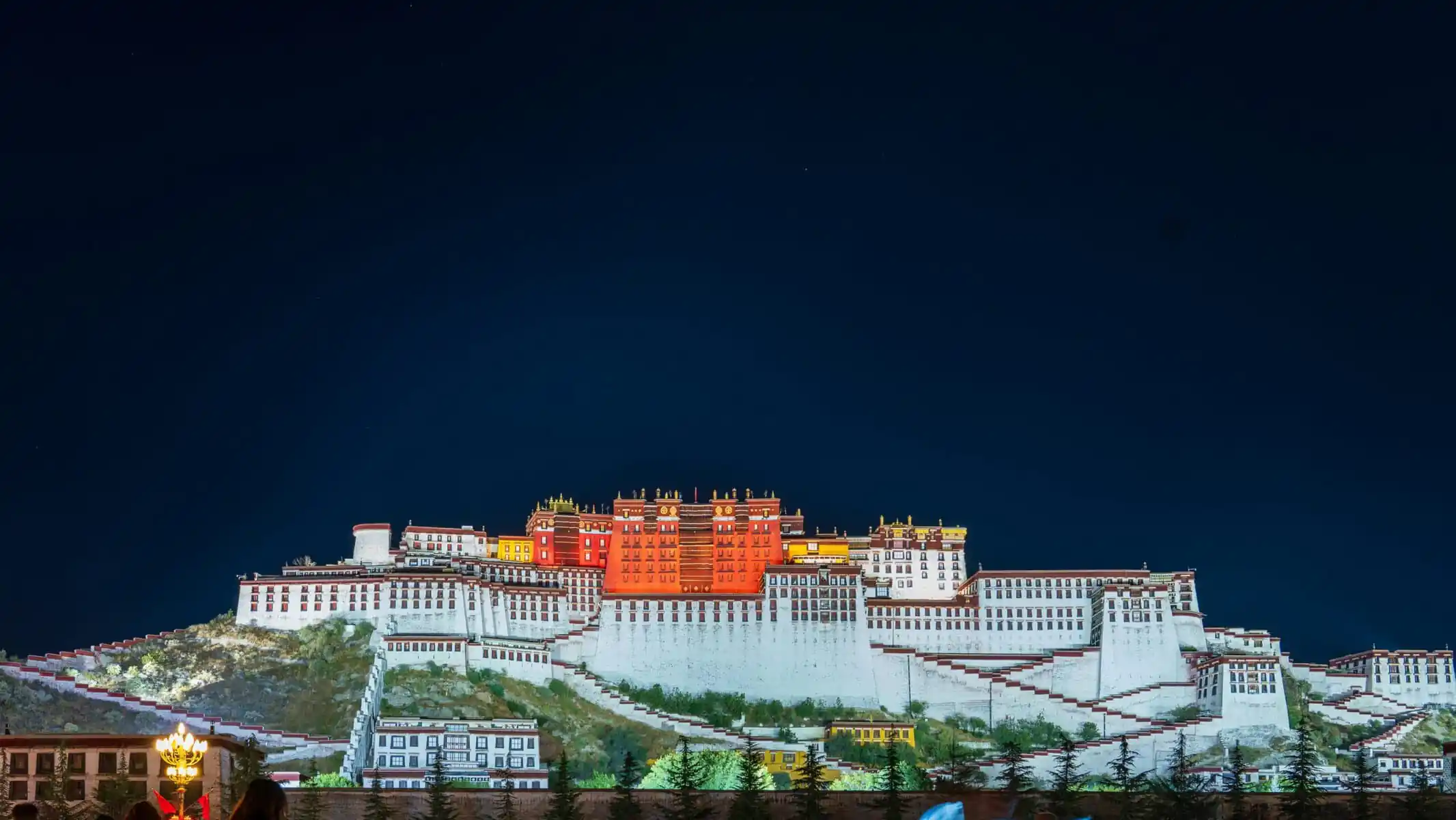 Potala Palace Tibet, china, china tour, Night view of the Potala Palace in Lhasa, with white and red tiered walls illuminated against a dark sky.