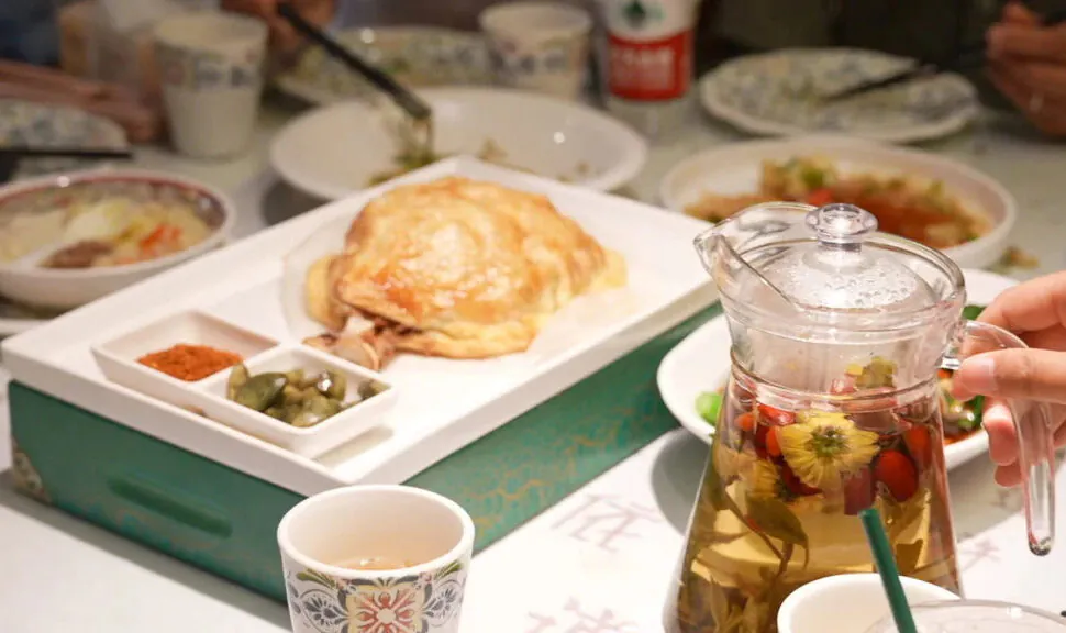 chinese food, china tour, Roasted chicken on a white tray with small condiment dishes, surrounded by bowls on a busy dining table.