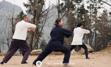 wudang taichi, hubei, china, chinaexplorertour, Three people practicing martial arts in an outdoor, rocky park with bare trees in the background.