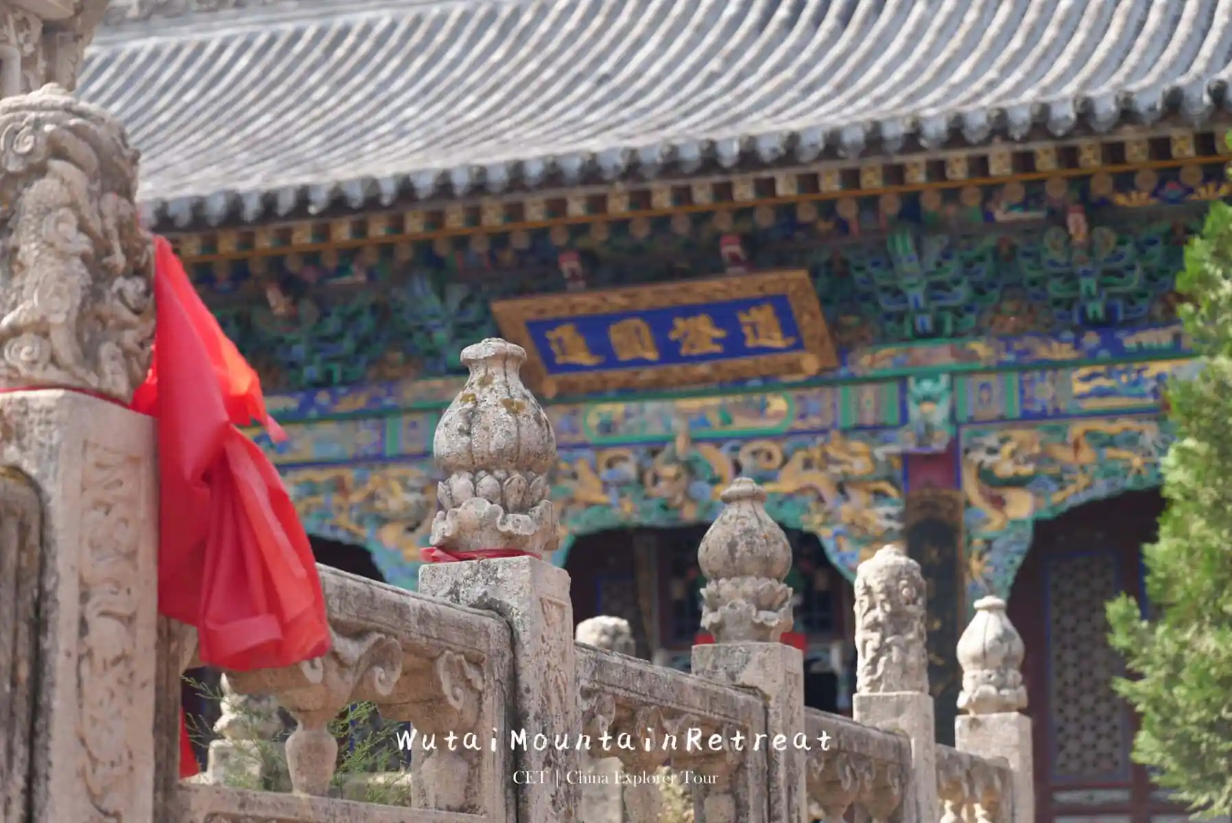 wutai retreat, shanxi, chinatrip, Stone carved balusters in a temple courtyard with a colorful, ornate temple facade in the background and red cloth draped on the railing.