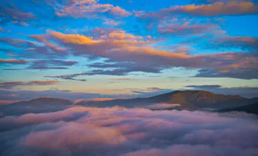 Mount Wutai, shanxi, china, china tour, Mountains rise above a sea of pink clouds under a blue-orange sunset sky, creating a tranquil alpine scene.