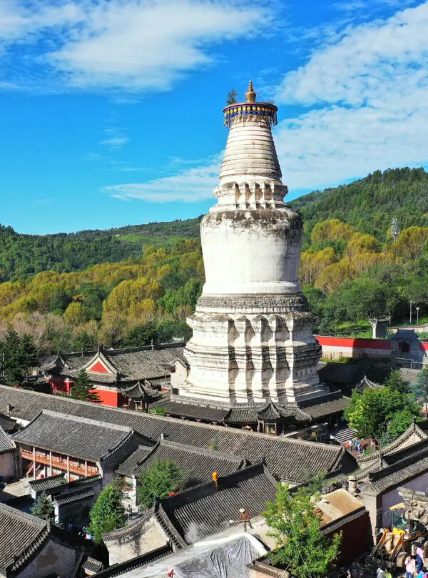 Mount Wutai, shanxi, china, china tour, White Buddhist stupa rising above a Chinese temple complex with gray tiled roofs and green hills in the background.