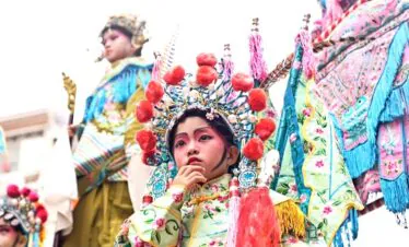 Chinese Lunar New Year, southern china, chinatrip, Young girl in a colorful traditional festival costume with an ornate headdress, preparing for a performance.