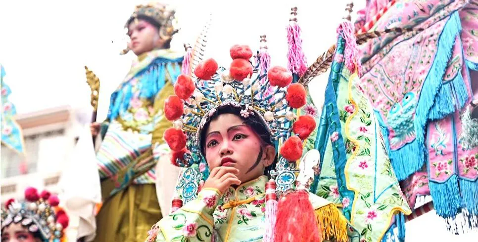 Chinese Lunar New Year, southern china, chinatrip, Young girl in a colorful traditional festival costume with an ornate headdress, preparing for a performance.