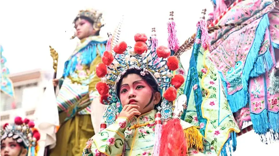 Chinese Lunar New Year, southern china, chinatrip, Young girl in a colorful traditional festival costume with an ornate headdress, preparing for a performance.