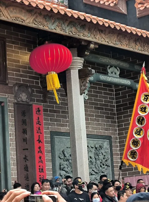 Zhanjiang, guangdong, china, chinatrip, Festive street scene in front of a Chinese temple with red lanterns, colorful banners, and a crowd of people participating in a celebration