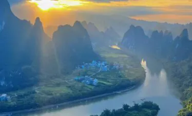 yangshuo, guangxi, china, chinatrip, Sunset over a winding river surrounded by towering karst mountains and a small village at riverbank.