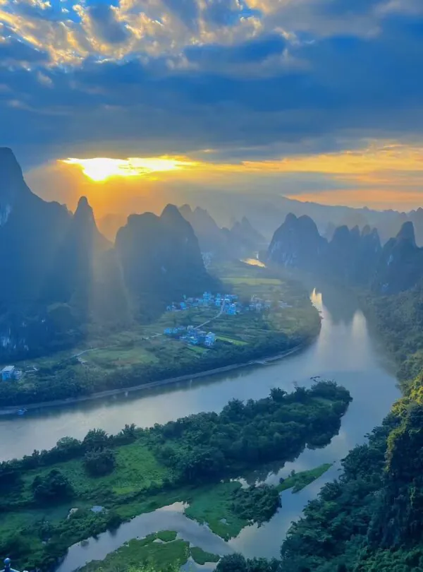 yangshuo, guangxi, china, chinatrip, Sunset over a winding river surrounded by towering karst mountains and a small village at riverbank.