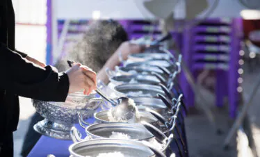 Mount Wutai, shanxi, china, china tour, Person in black coat serving food from a row of steaming metal chafing dishes at a buffet line.