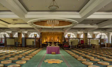 Pushou Temple, Mount Wutai, shanxi, china, china tour, A Buddhist meditation hall with a central altar, cushions arranged in rows, and a gold statue at the back under warm lights.