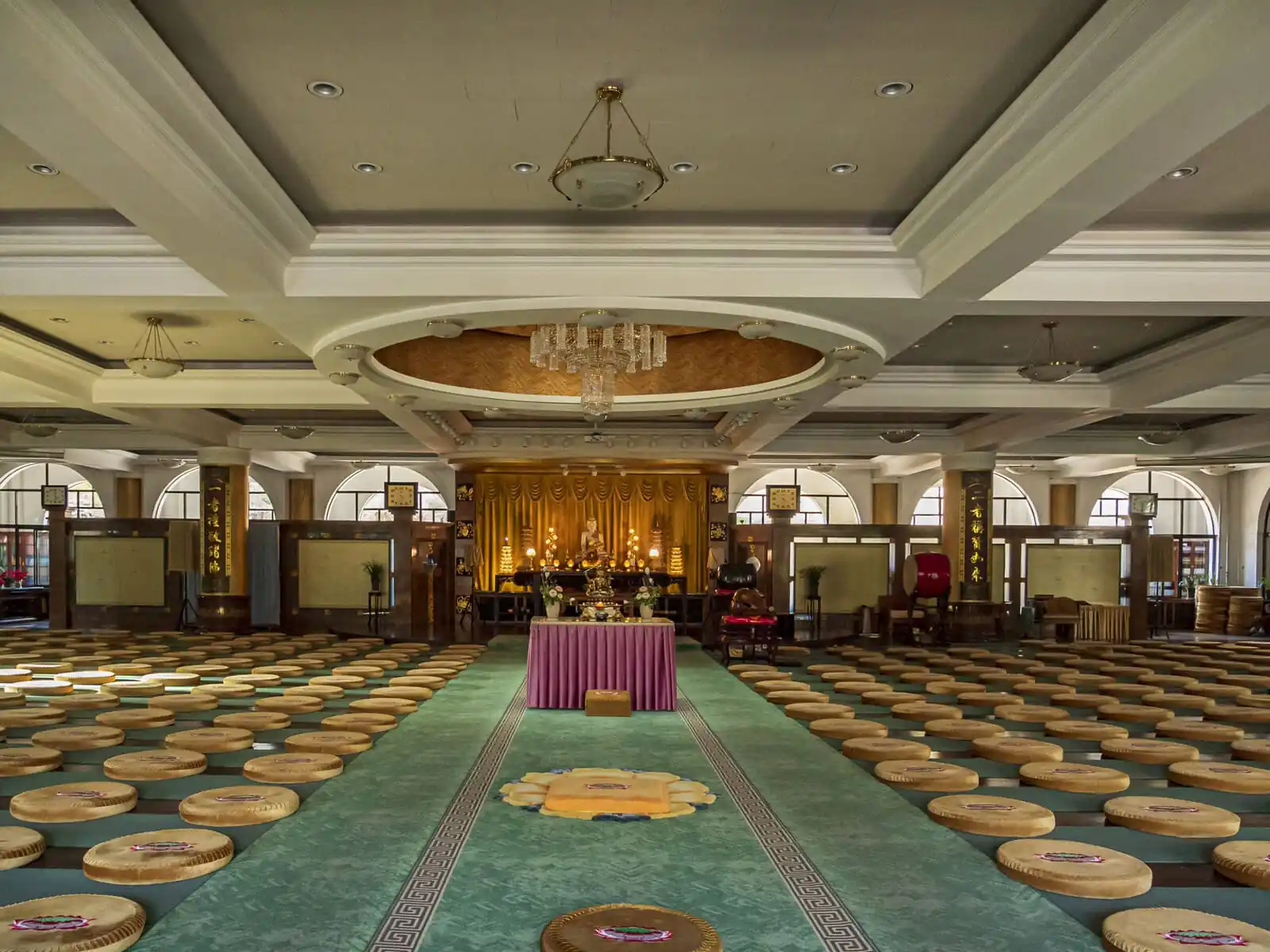 Pushou Temple, Mount Wutai, shanxi, china, china tour, A Buddhist meditation hall with a central altar, cushions arranged in rows, and a gold statue at the back under warm lights.