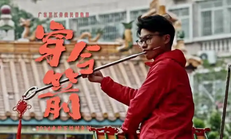 Chinese New Year Festival: A Deep Dive into the Tradition and Joy, china tour, Young man in a red hoodie performs with a long pole in front of a tiled roof, with bold red Chinese characters overlaying the scene.