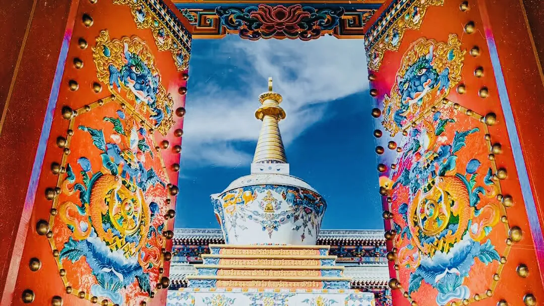 wutai mountain, shanxi, chinaexplorertour, Colorful ornate temple gate opening to a white-and-gold stupa under a bright blue sky, with dragon motifs on red pillars.