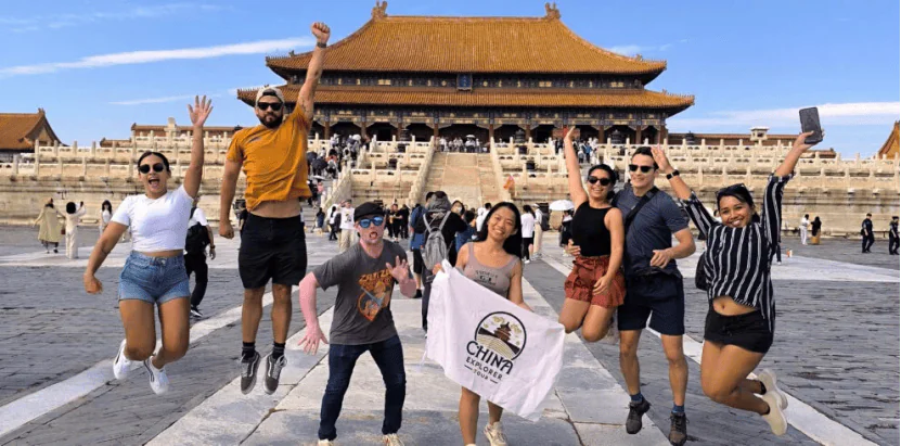 Forbidden City, beijing, chinatravel, Eight friends jump in the air in front of Beijing's Forbidden City, holding a white flag with a logo.