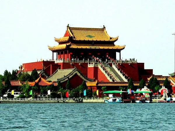 longting park, kaifeng, henan, chinatrip, Traditional Chinese palace on tiered red terraces with a yellow roof along a lakeside; visitors climb the stairs.