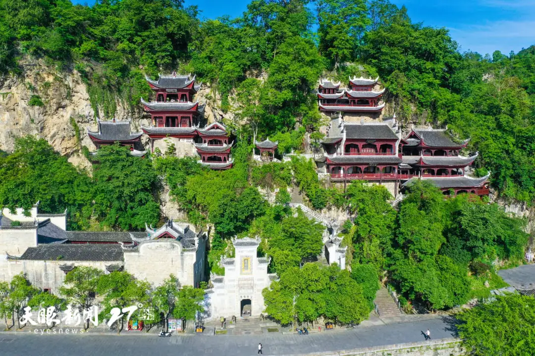 ancient architecture group of tsing lung hole, guizhou, china tour, Cliffside temple complex with stacked red pagodas rising among green trees and a stone gate at the base.