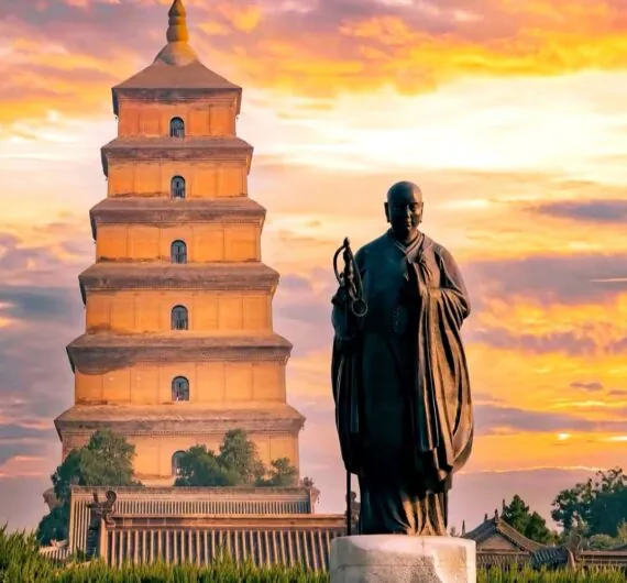 Big wild goose Pagoda, xi'an, shaanxi, chine tour, Statue of a Buddhist monk in robes standing before a seven-tiered pagoda at sunset, with an inscribed rock in the foreground.
