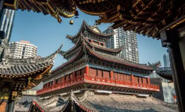Luohan Temple, Arhat Temple, chongqing, chinatrip, Red multi-tiered Chinese temple with ornate upturned eaves framed by modern high-rise buildings in a cityscape