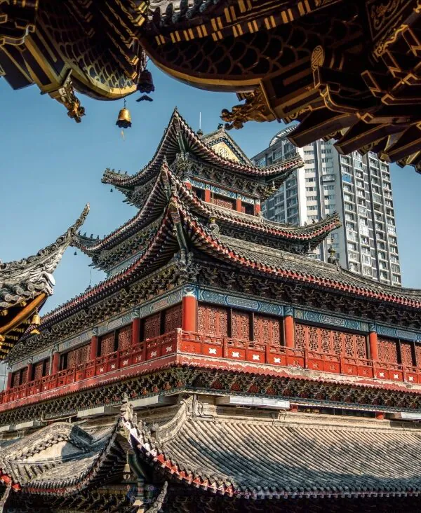 Luohan Temple, Arhat Temple, chongqing, chinatrip, Red multi-tiered Chinese temple with ornate upturned eaves framed by modern high-rise buildings in a cityscape
