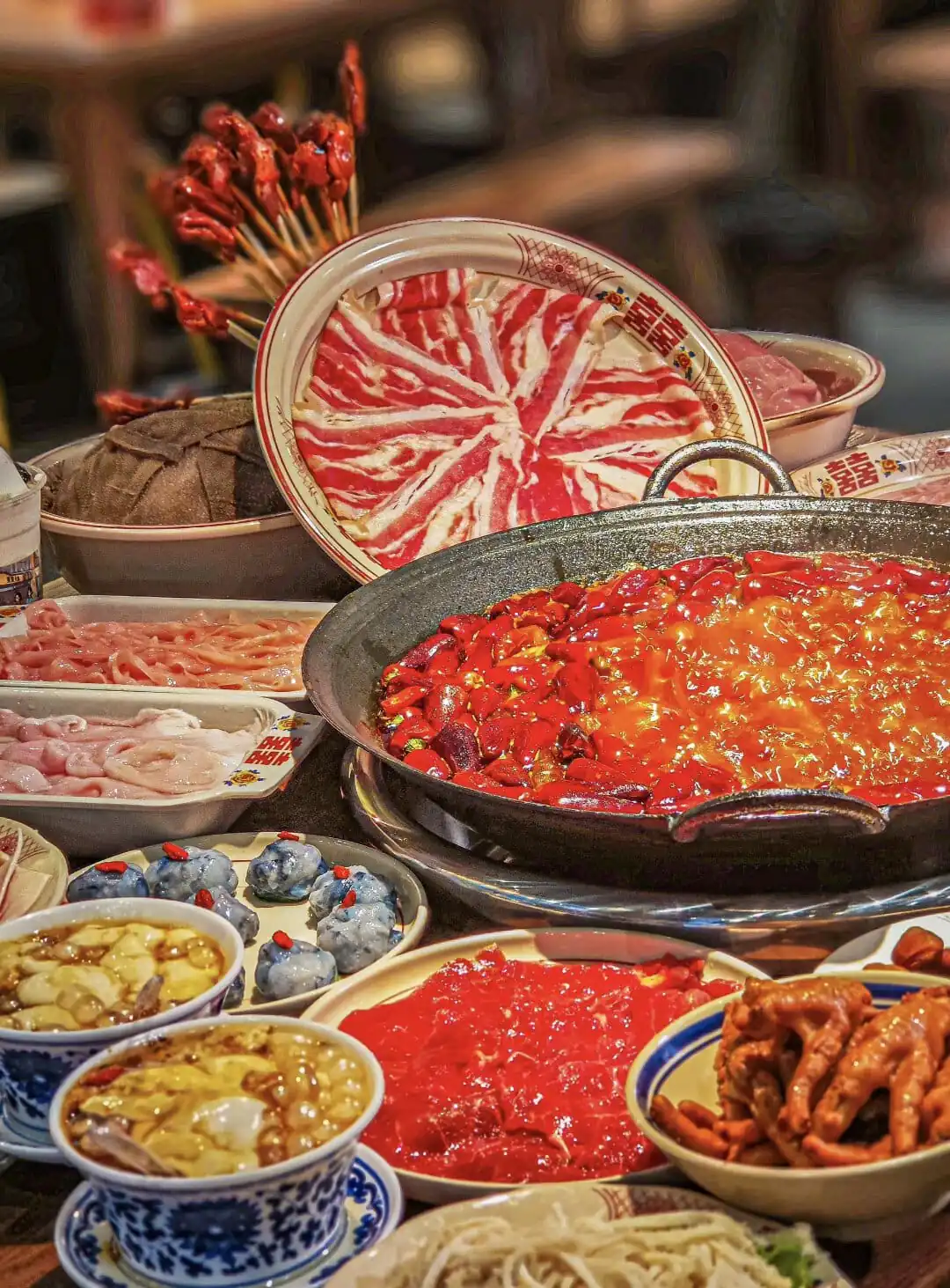 Hotpot, chongqing day tour, chinatrip, Large hot pot with a fiery red broth and chopped chilies, surrounded by raw meats and side dishes for a communal meal.