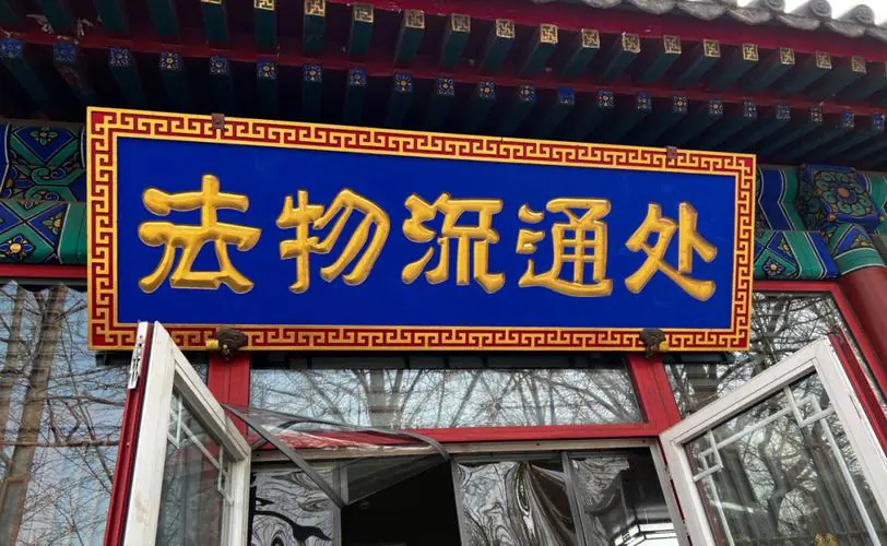 Yonghe Temple official Spiritual Gift Shop, beijing, chinatrip, Blue sign with gold Chinese characters mounted above an open doorway in a traditional Chinese building surface decorate with red trim and ornate frame.