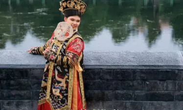 hanfu photoshoot, the forbidden city, beijing, qing dynasty, female, solo, chinatrip, Woman in an ornate Chinese imperial costume with dragon embroidery, standing by a stone railing beside a calm, green pond