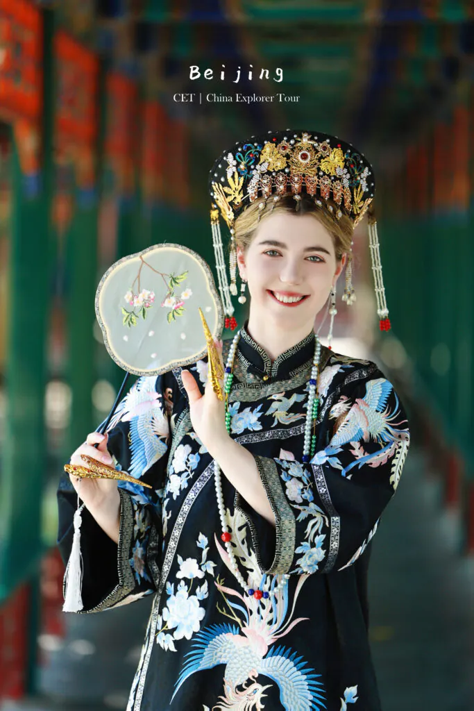 hanfu photoshoot, zhongshan park, beijing, female, solo, chinatrip, Smiling woman in an ornate traditional Chinese headdress and robe, holding a round embroidered fan.