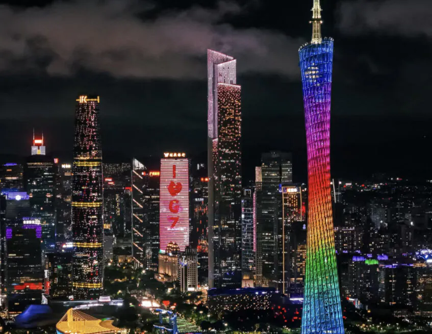 Guangzhou skyline at night featuring the Canton Tower lit in rainbow colors beside the river.