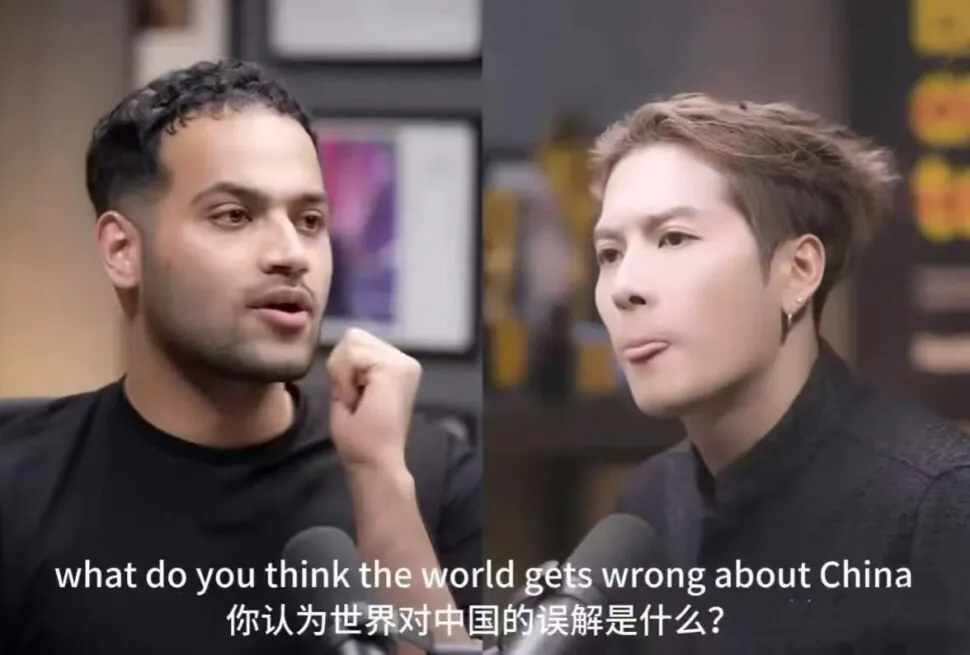Split-screen interview with a man and a woman speaking into microphones, subtitles visible in English and Chinese below the frame.