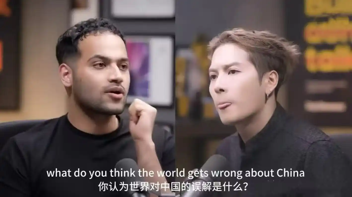 Split-screen interview with a man and a woman speaking into microphones, subtitles visible in English and Chinese below the frame.