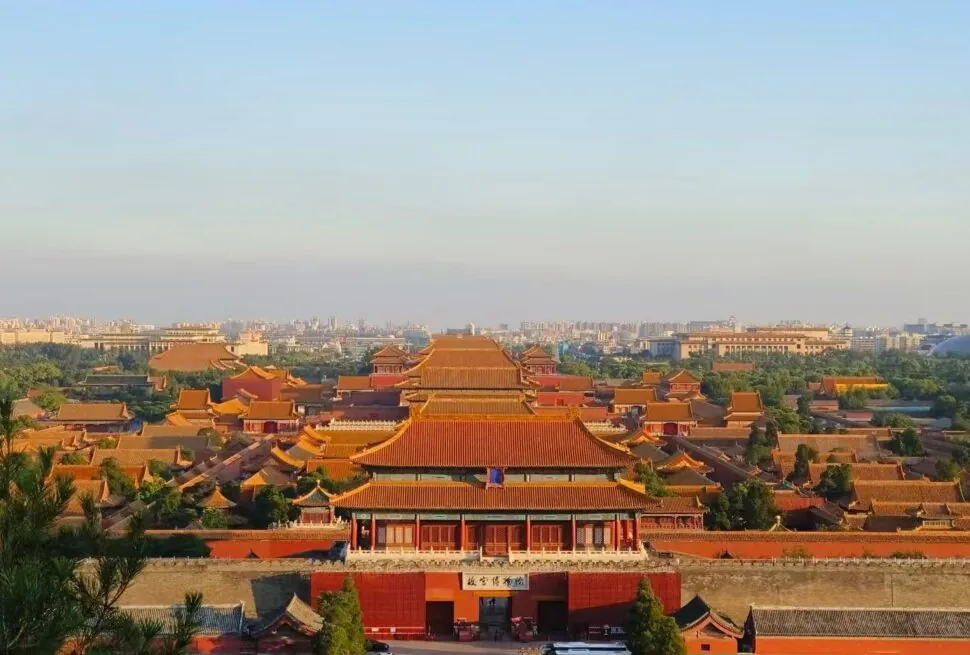 Jingshan Park,Beijing,Chinatour Panoramic view of the Forbidden City in Beijing, with red walls, golden-tiled roofs, and a distant city skyline on the horizon.