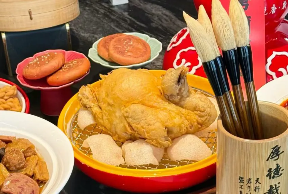 Top Family Restaurants Near the Terracotta Warriors for Kids,Xi`an,Chinatour Festive Chinese banquet with a fried whole chicken in a yellow dish, buns, and a wooden brush holder with calligraphy on the right.