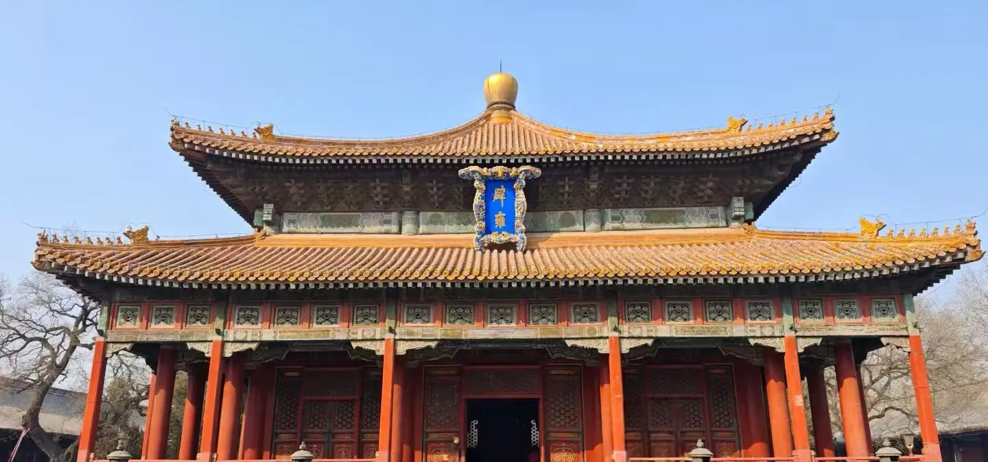 Confucius Temple and Imperial College,Beijing,Chinatour Front view of a traditional Chinese temple with orange tiled roof, red columns, and carved wooden doors against a clear blue sky.