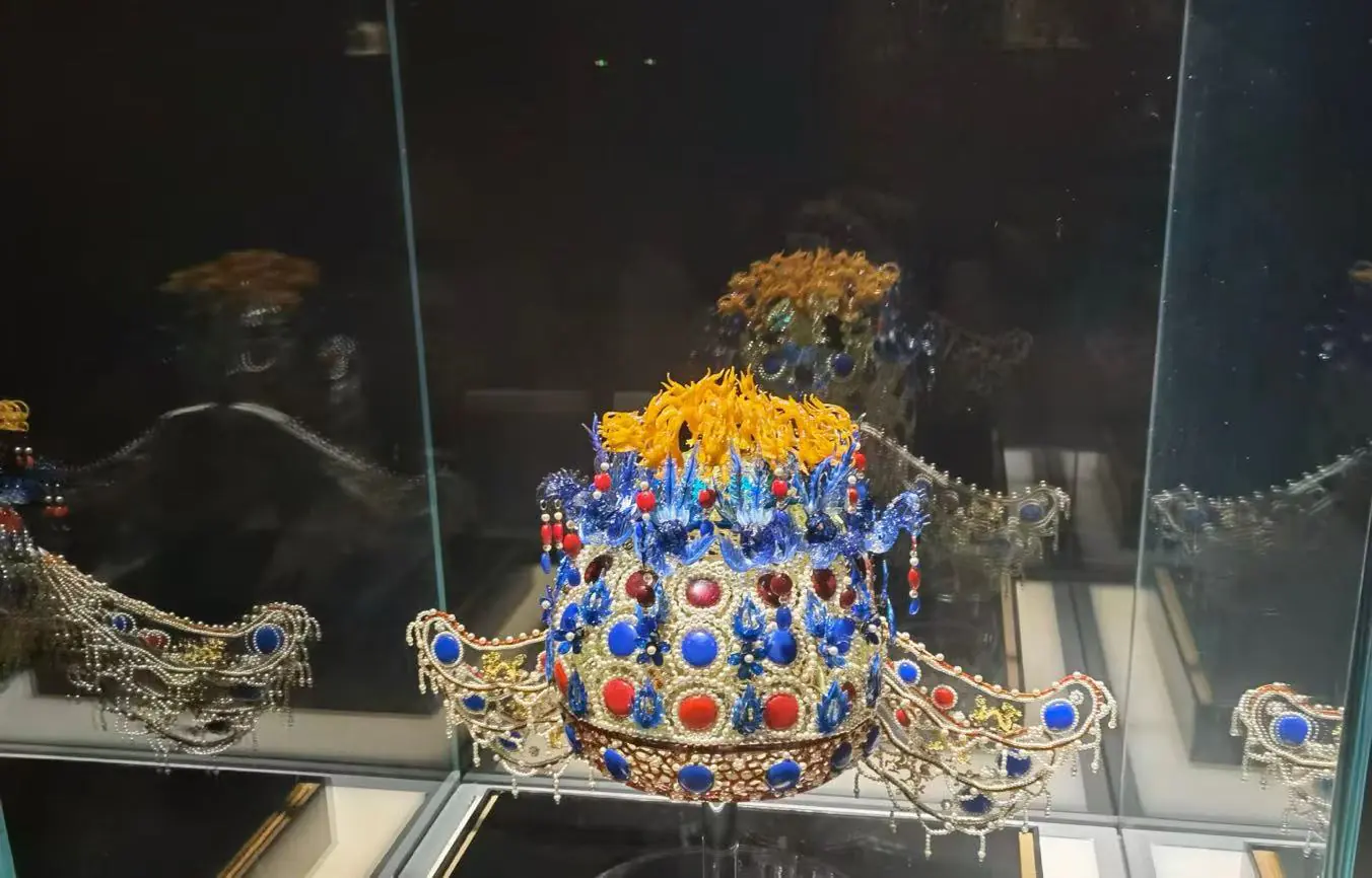 National Museum of China,Beijing,Chinatour Ornate jeweled crown with blue and red gems and a yellow floral top, displayed in a glass case