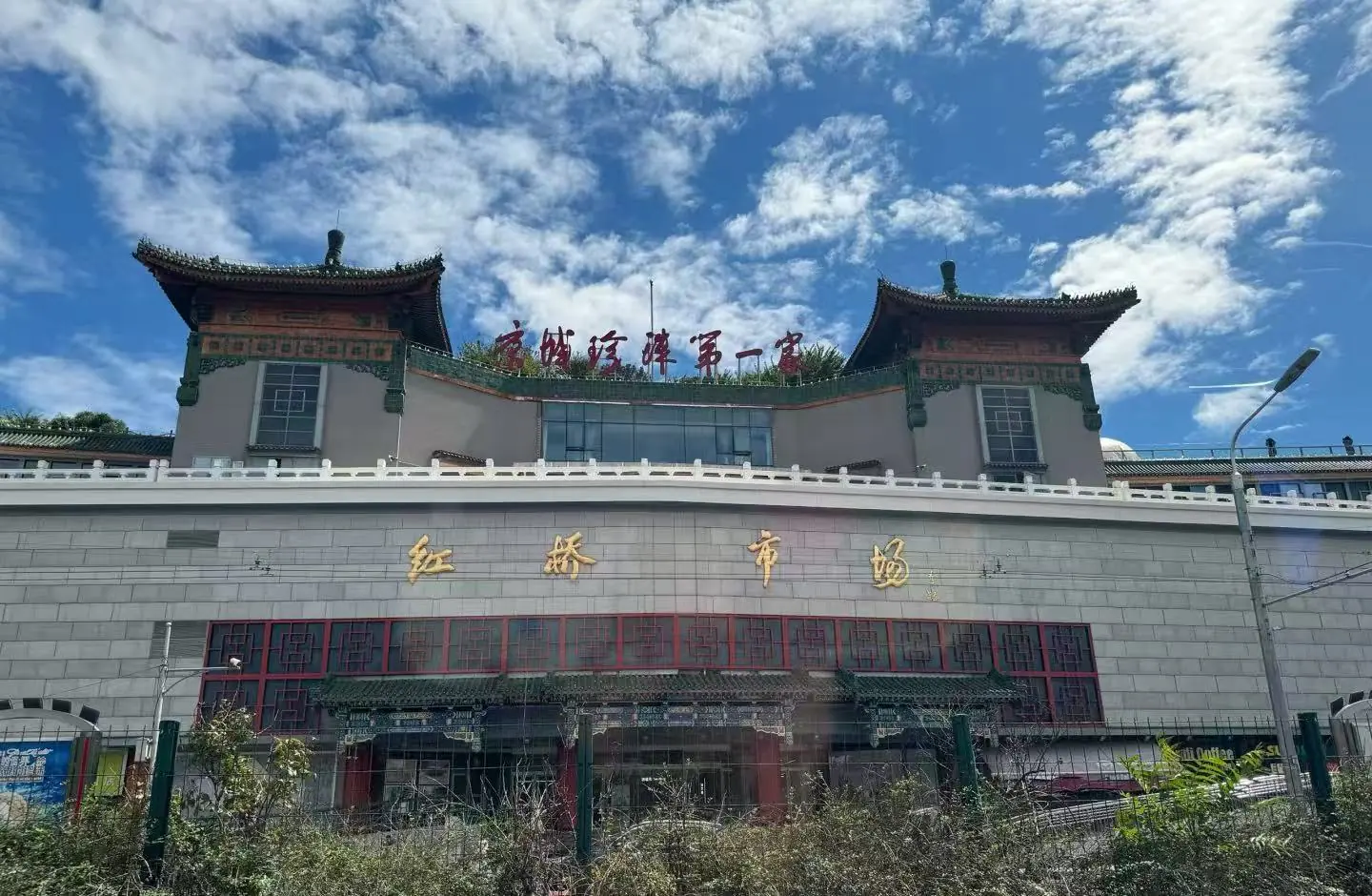 Hongqiao Pearl Market,Beijing,Chinatour Front view of a building with traditional Chinese pagoda-style roofs, gold Chinese characters on the wall, and red-windowed doors beneath a blue sky.