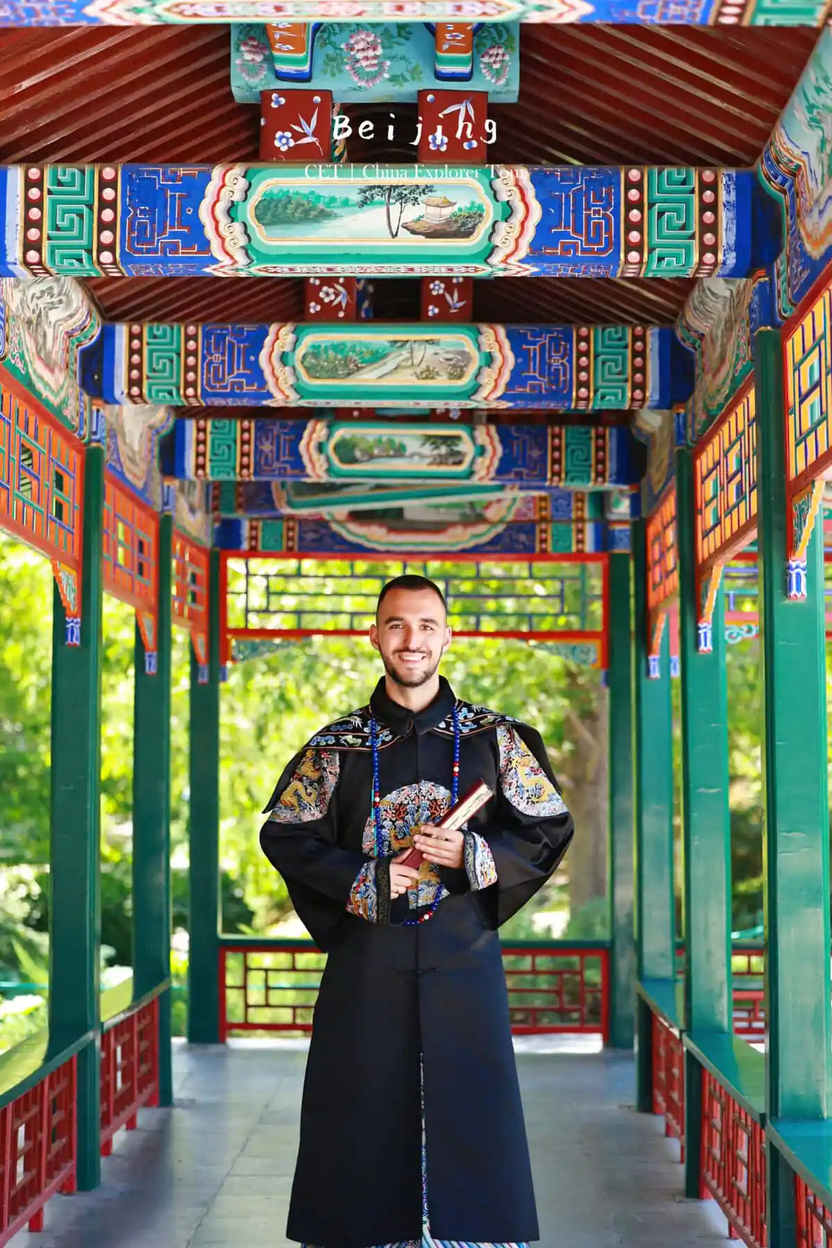 hanfu photoshoot, the forbidden city, beijing, qing dynasty, male, solo, chinatravel, Smiling man in a dark traditional Chinese robe stands in a vibrantly painted temple corridor.