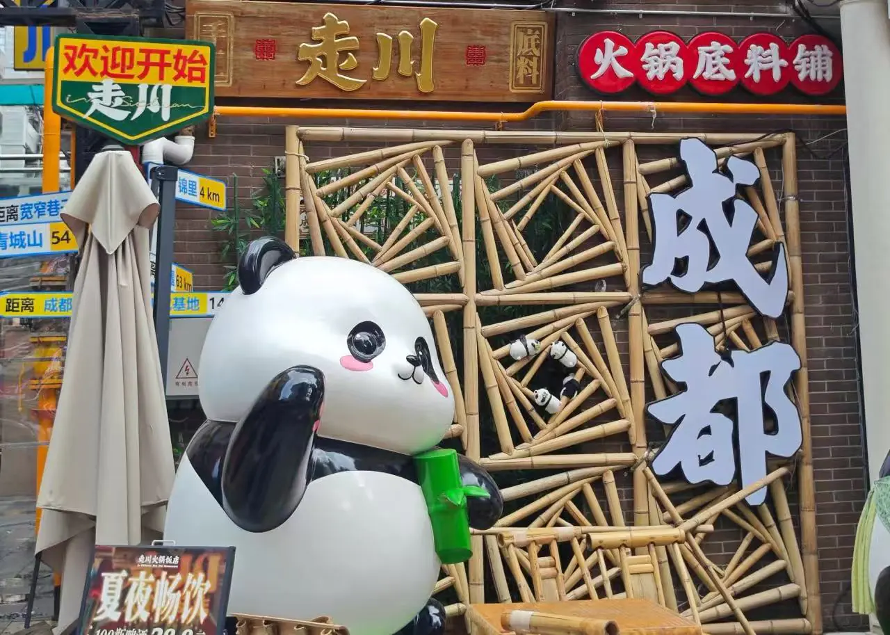 Front of a Chinese hotpot restaurant with a large panda statue holding a green cup, a bamboo lattice facade, and big white Chinese characters on the right.