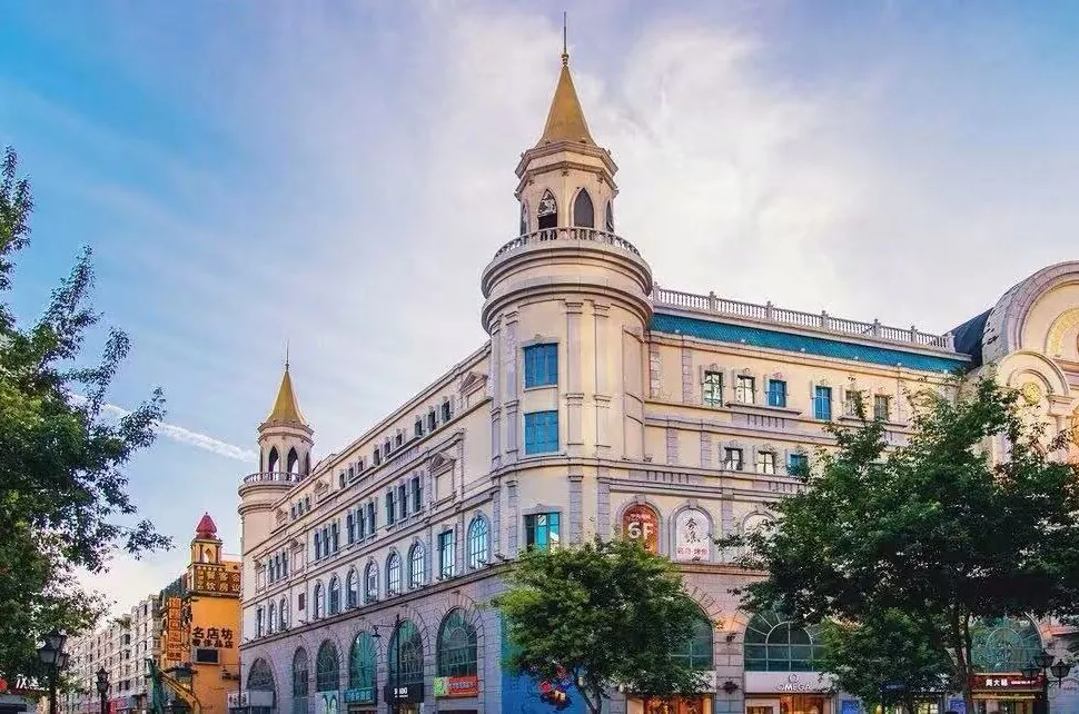 Harbin Central Street,Harbin,Chinatour Historic European-style shopping arcade with two tower spires and arched storefronts along a tree-lined street on a sunny day.