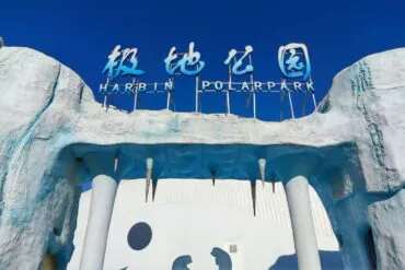 Harbin Polarland,Harbin,Chinatour Entrance to Harbin Polar Park with an icy blue arch and a blue sign reading 'Harbin Polar Park' against a clear sky.