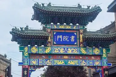 Shuyuanmen Ancient Cultural Street,X`an,Chinatour Colorful traditional Chinese paifang with ornate dragons and blue signboard at the center, in a street setting