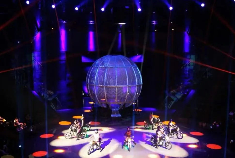 Shanghai Circus World,Shanghai,Chinatour Stage show with a large lit globe centerpiece surrounded by motorbikes performing on circular spotlights. Purple and orange lighting.