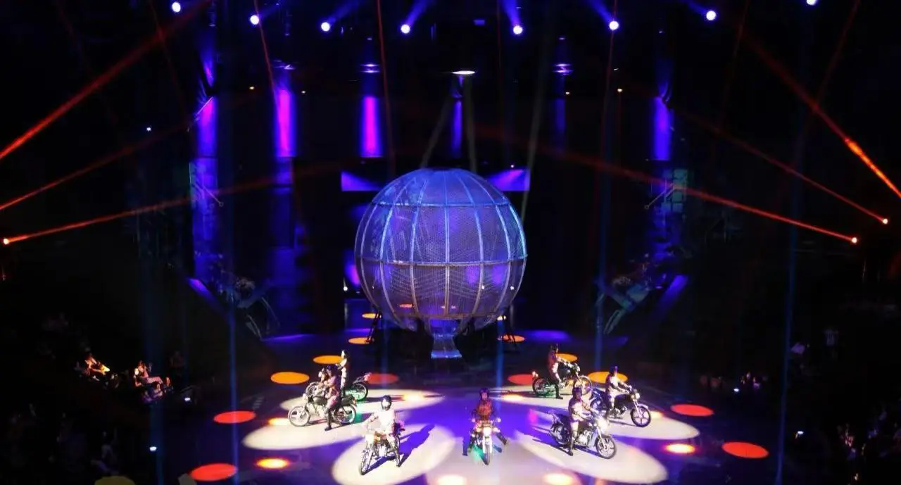 Shanghai Circus World,Shanghai,Chinatour Stage show with a large lit globe centerpiece surrounded by motorbikes performing on circular spotlights. Purple and orange lighting.