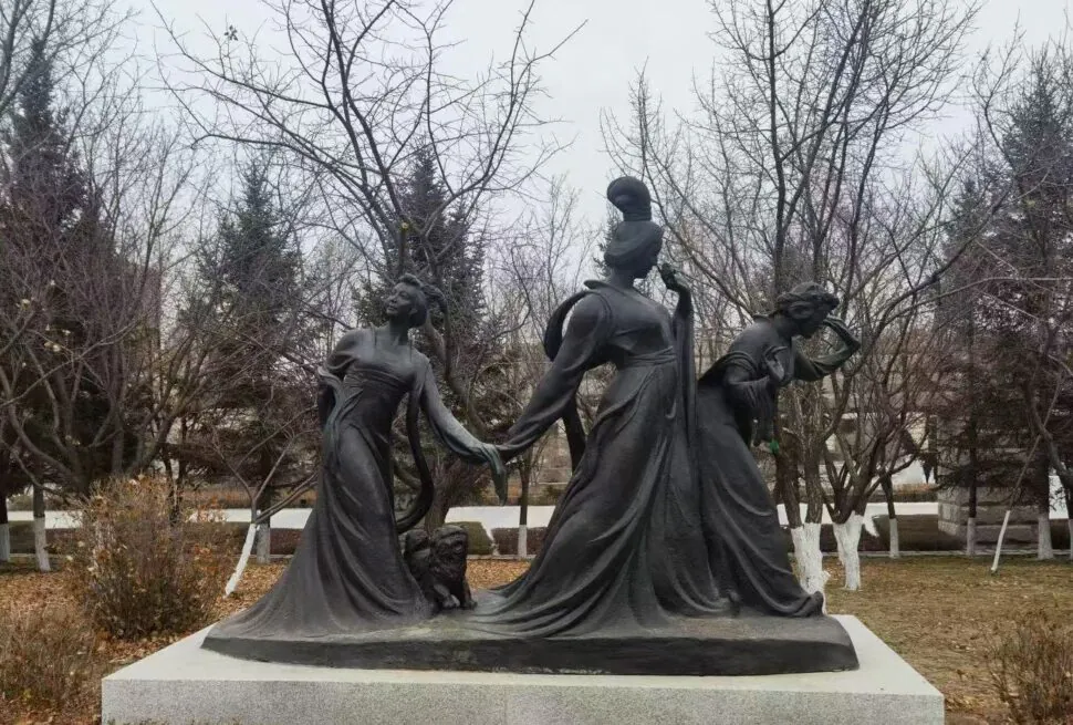 Changchun World Sculpture Park,Changchun,Chinatour Bronze sculpture of three figures in flowing robes on a stone pedestal in a park.