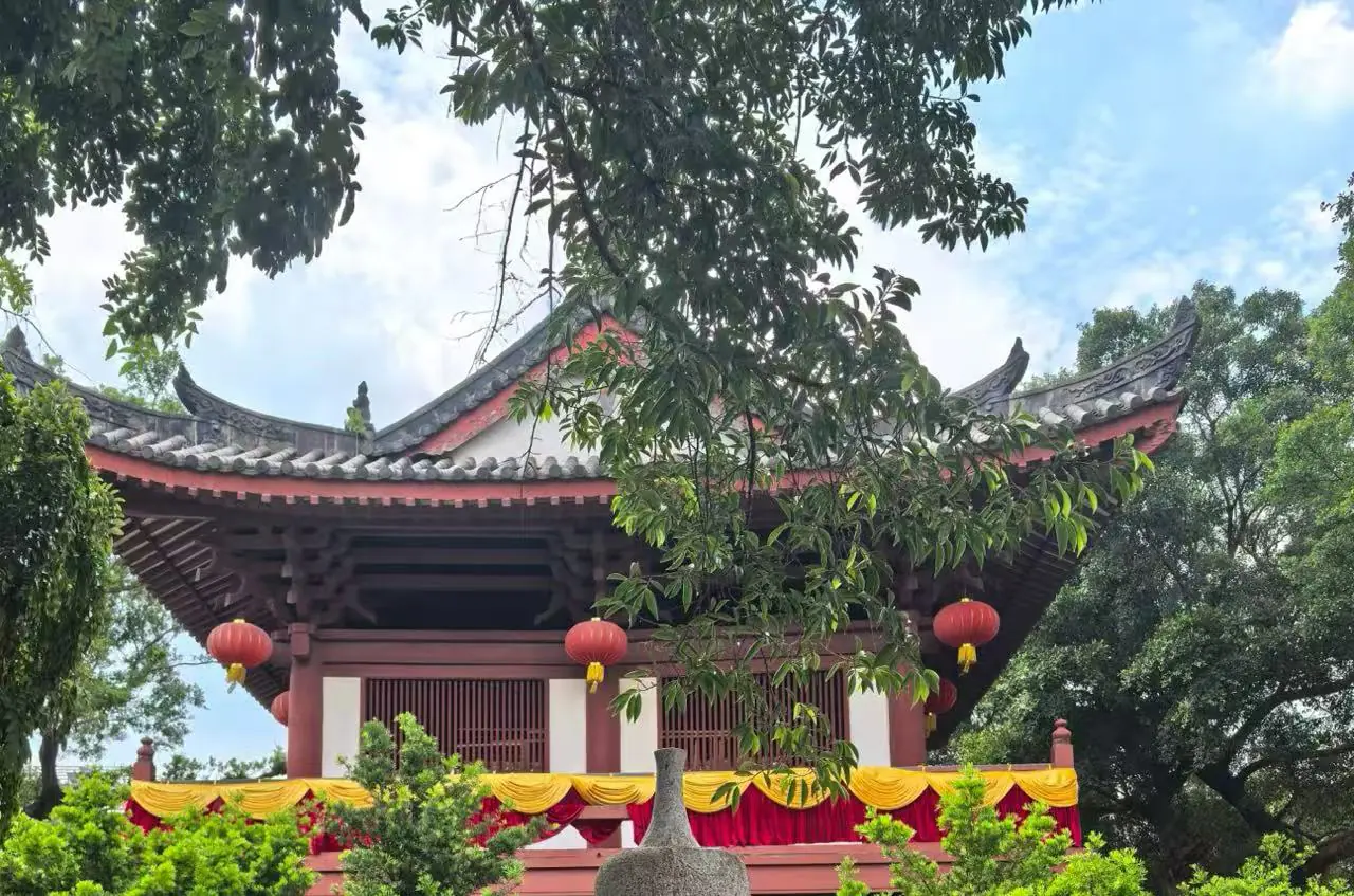 Guangxiao Temple,Guangzhou,Chinatour Traditional Chinese pavilion with curved tiled roof, red lanterns, and yellow drapery in a lush garden.