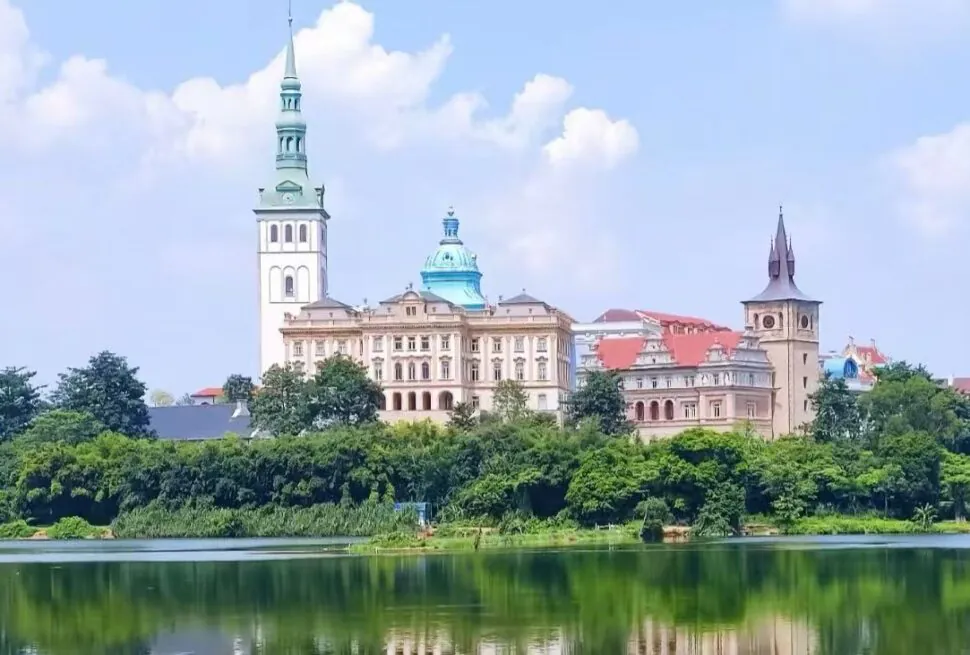 Songshan Lake,Dongguan,Chinatour European-style castle complex with tall spires by a tree-lined riverfront, reflection in the water