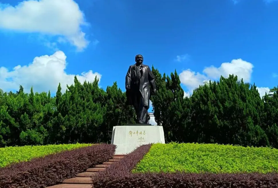 Lianhua Mountain Park,Shenzhen,Chinatour Bronze statue of a man in a suit standing on a pedestal in a landscaped park with shrubs and steps.