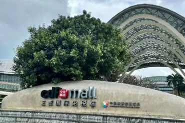 Facade sign reading 'cdf mall' with Chinese characters, a large tree behind, and curved glass arches in the background.